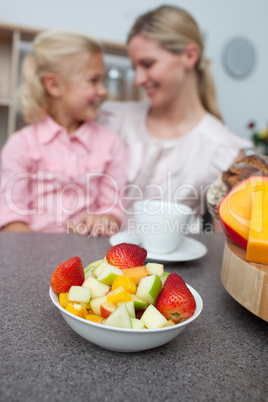 Blond little girl eating strawberry with her mother