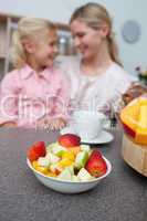 Blond little girl eating strawberry with her mother