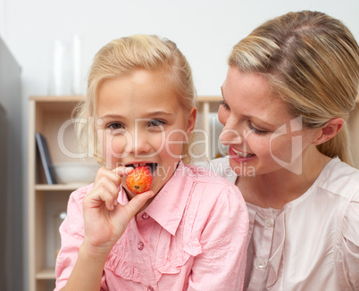 Lively little girl eating fruit with her mother