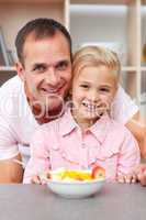 Happy little girl eating fruit with her father