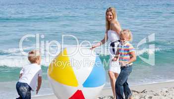 Cheerful mother and her children playing with a ball