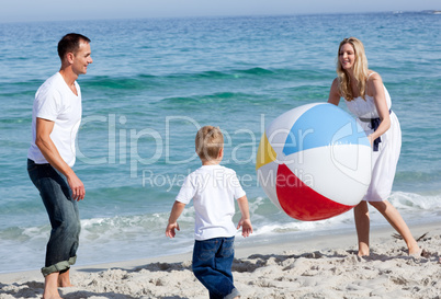 Happy parents and their son playing with a ball