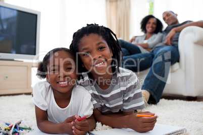 Smiling children drawing lying on the floor