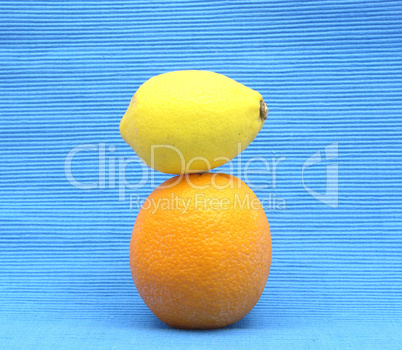 Zitrone auf Orange gestapelt auf blauem Hintergrund Zitrone auf Orange gestapelt auf blauem Hintergrund