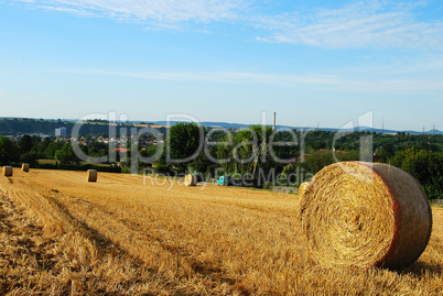 Hay field with round haystacks and the village