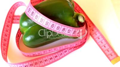 Tape measure wrapped around rotating green pepper