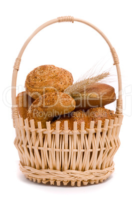 Fresh buns and ears of wheat in a basket on a white background