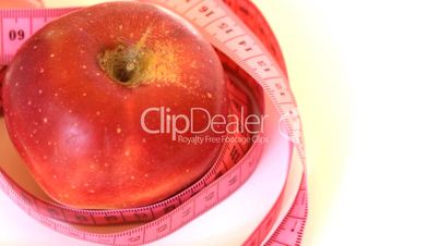 Tape measure wrapped around rotating red apple, loopable