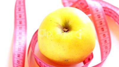 Tape measure wrapped around rotating yellow apple, loopable
