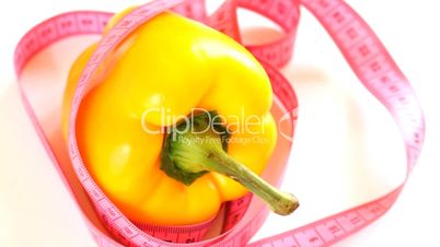 Tape measure wrapped around rotating yellow pepper, loopable