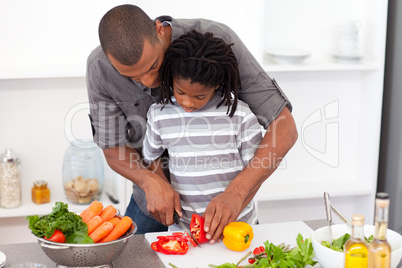 Loving father helping his son cut vegetables