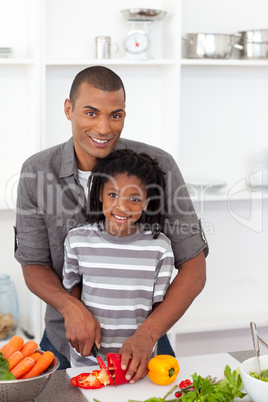 Smiling father helping his son cut vegetables