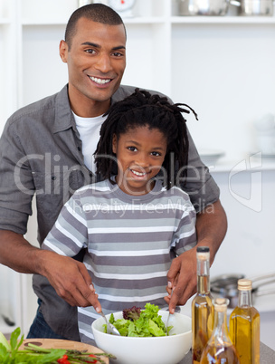 Smiling little boy preparing salad with his father