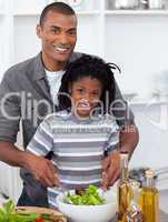 Smiling little boy preparing salad with his father