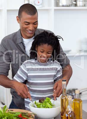 Adorable little boy preparing salad with his father