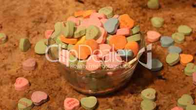 Valentine candy hearts dropping into bowl