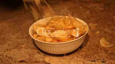 Potato chips dropping into bowl slow motion