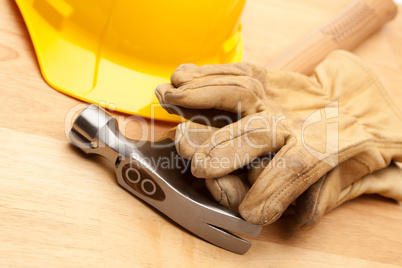 Yellow Hard Hat, Gloves and Hammer on Wood