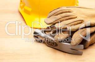 Yellow Hard Hat, Gloves and Hammer on Wood