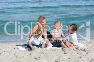 Caring parents with their children sitting on the sand