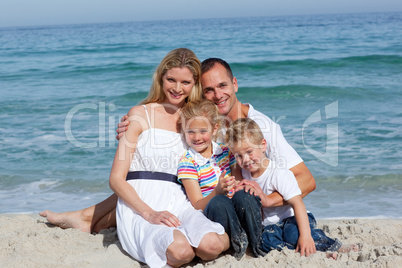 Portrait of a cheerful family sitting on the sand