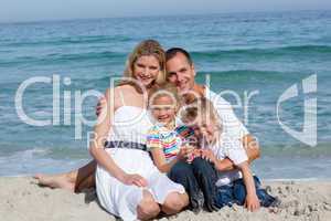 Portrait of a cheerful family sitting on the sand