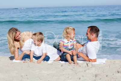 Happy family sitting on the sand