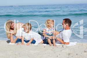 Happy family sitting on the sand