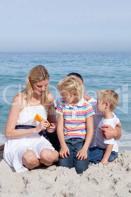 Attentive mother holding sunscreen at the beach