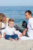 Happy parents with their son sitting on the sand