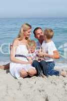 Cute children and their parents sitting on the sand