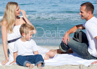 Smiling parents with their son sitting on the sand