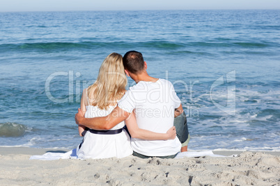Affectionate couple sitting on the sand at the beach