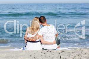 Affectionate couple sitting on the sand at the beach