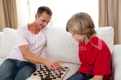 Attentive father playing chess with his son