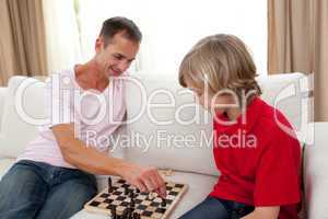 Attentive father playing chess with his son