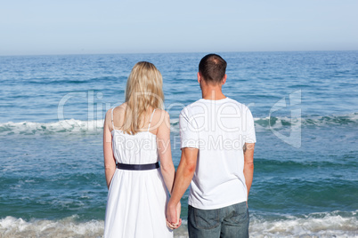 Enamored couple holding hands at the shore line