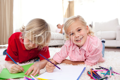 Cheerful children drawing lying on the floor