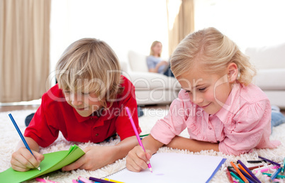 Adorable siblings drawing lying on the floor