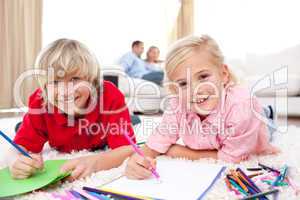 Lively siblings drawing lying on the floor