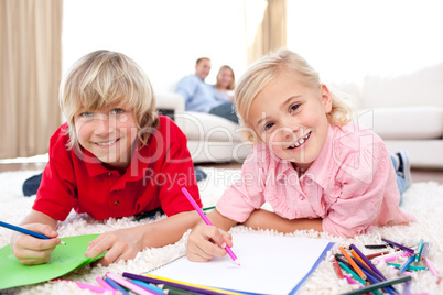 Happy siblings drawing lying on the floor