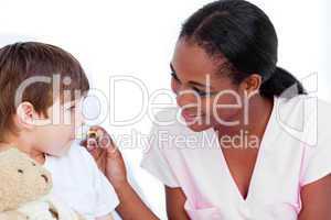 Smiling nurse taking little boy's temperature