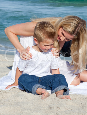 Attentive mother with her son sitting on the sand