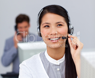 Youg asian businesswoman with headset on at her desk