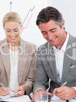 Cheerful business people writting notes in a meeting