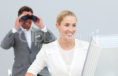 Ambitious manager holding binoculars looking at his colleague's