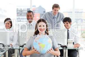 Brunette businesswoman and her team showing a terrestrial globe