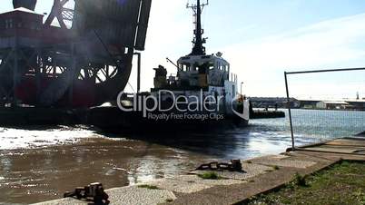 Tug straining to pull tanker into docks