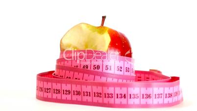 Tape measure wrapped around rotating bitten apple, loopable