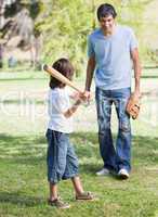 Cute little boy playing baseball with his father